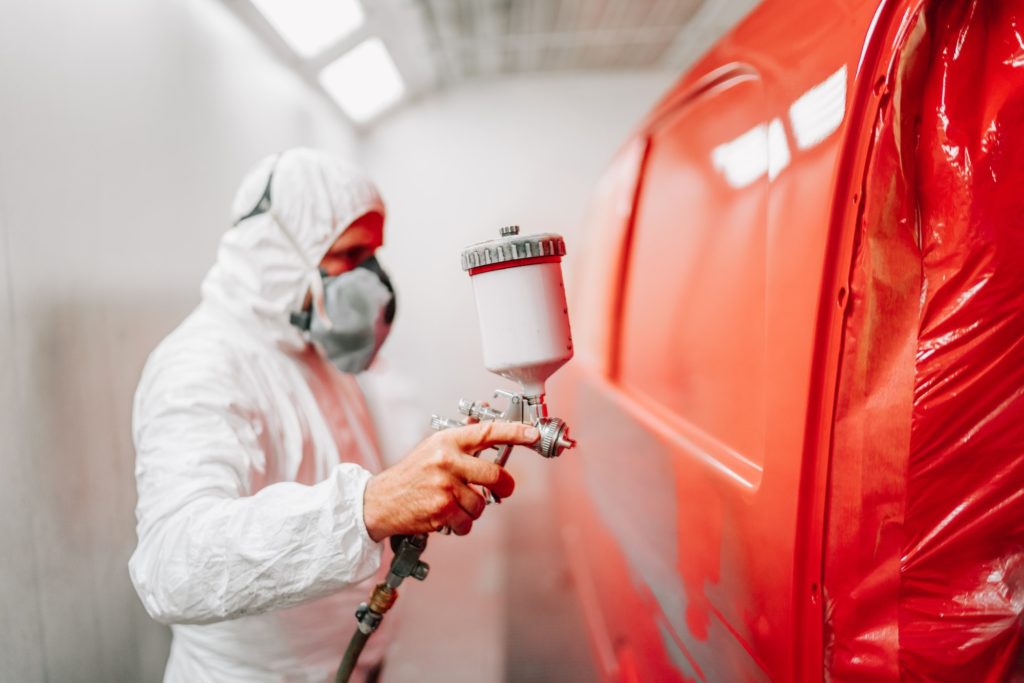 worker painting a car using a paint spray gun